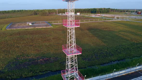 A Drone Rises Above a Metal Lighting Tower in an Oil and Gas Field