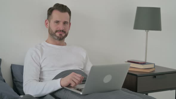 Man with Laptop Showing Thumbs Up in Bed