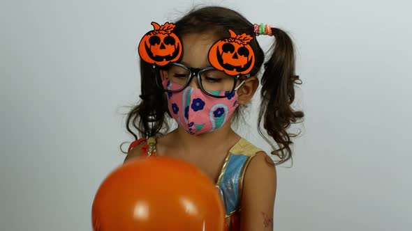 Happy Halloween. The girl plays with balloons and laughs. Girl wearing a Covid-19 mask on Halloween.