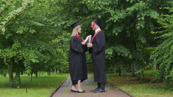 Windy Weather Pair of Graduates Standing in Park With Diplomas Wind of Change