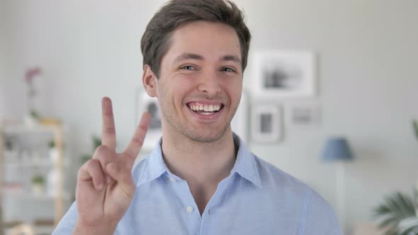 Victory Sign by Positive Handsome Young Man