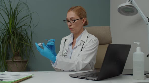 Female Doctor in Protective Gloves Filling Syringe with Vaccine Indoor