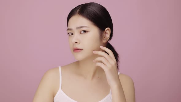 Close up face of young Asian woman worry about face skin problem on pink background.