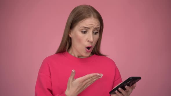 Disturbed girl with ginger hair has problematic concerned face expression, holding smartphone