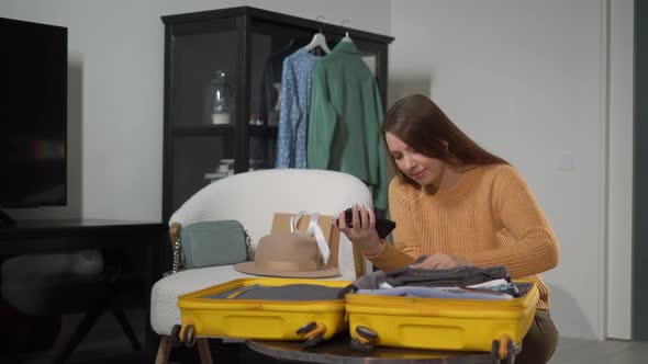 A Young Woman is Packing Her Suitcase