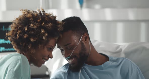 Black Wife Visiting and Talking with Patient Husband in Hospital Bed