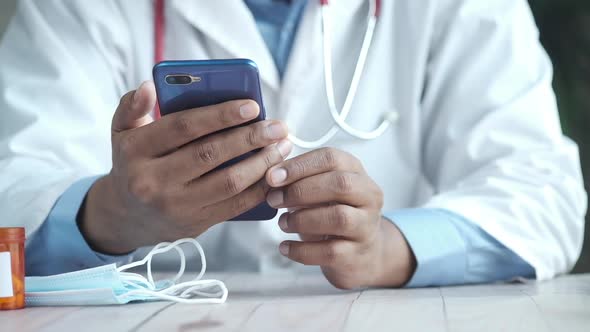 Doctor in White Coat Using a Smartphone While Sited