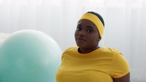 Upset Black Overweight Woman Wearing Yellow Fitness Headband Sadly Looking At Camera
