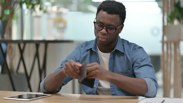 Young African Man Checking Empty Wallet While Sitting in Office