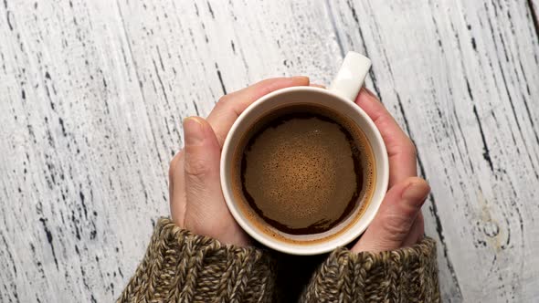 Morning Addictive Refreshment. Woman in Sweater Holding a Cup of Coffee in Her Hands. Brown Drink