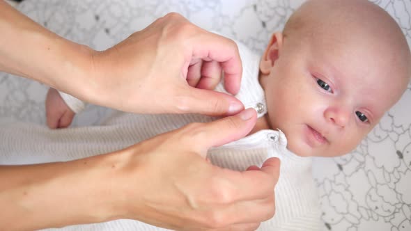 Mothers Hands Dressing Her Little Baby Girl. Closeup