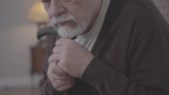 Close-up of Depressed Old Man Putting Head on Cane Stick and Thinking. Portrait of Desperate Elderly