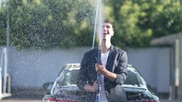 Laughing Man Spraying Foam with High Pressure Water Jet in Slow Motion Looking at Camera