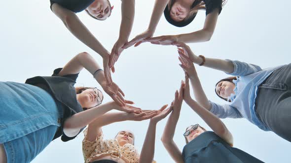 Friends Make a Circle with Their Palms Against the Blue Sky