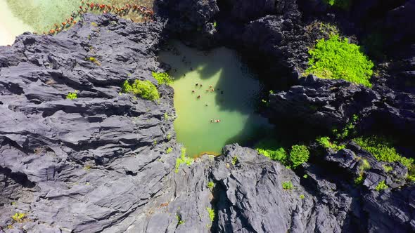 Tourists swim inside a tiny hidden tropical lagoon surrounded by cliffs in Miniloc