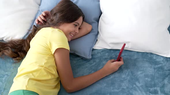 Cheerful Kid Messaging on Phone in Bed Email