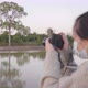 Back view close up of Asian woman standing and taking a picture of boat by the river - VideoHive Item for Sale