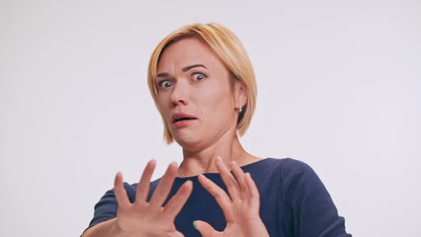 Scared Middleaged Caucasian Blonde Female in Blue Sweatshirt Playing Pantomime Pushing Away on White