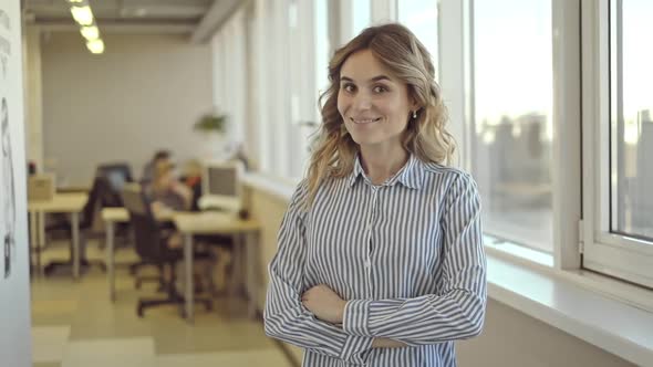 Young Confident Businesswoman Posing and Smiling for Camera While Working Day in Office