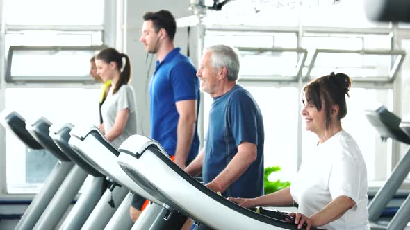 Senior Woman Running on Treadmill at Gym.