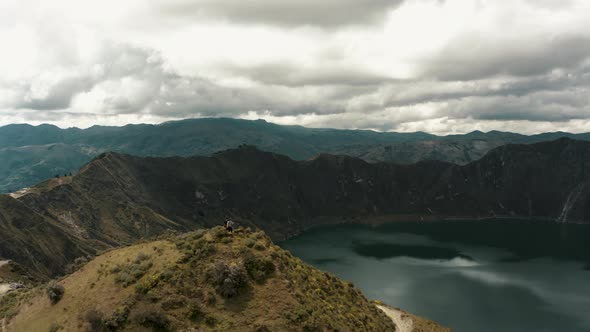 People on mountaintop admiring beautiful crater lake view and volcano scenery in Ecuador