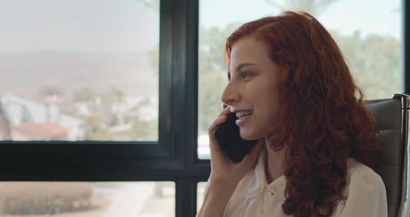 Close up of a business woman ending a phone call while sitting in her office. Slow motion.