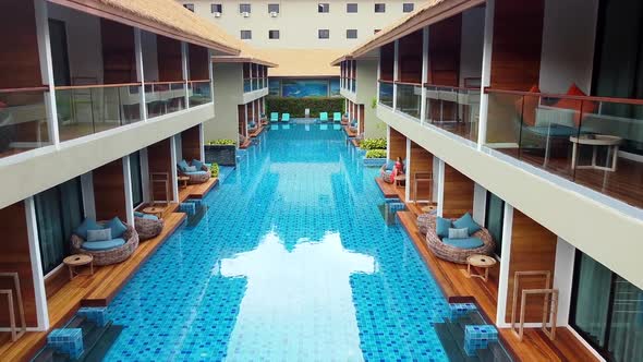 Drone Flying Over Blue Swimming Pool in Luxury Resort Between TwoStory Building