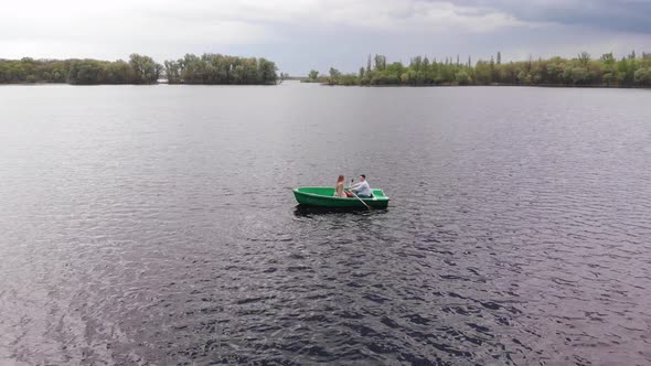 Drone Shooting of a Young Girl and Man on a Rowboat on the River During a Country Walk on a Summer