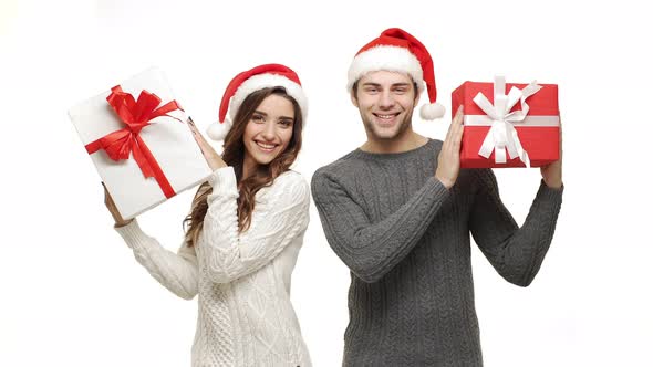  Young Couple Playing and Hiding Behind Christmas Present Box on White Isolated Background.