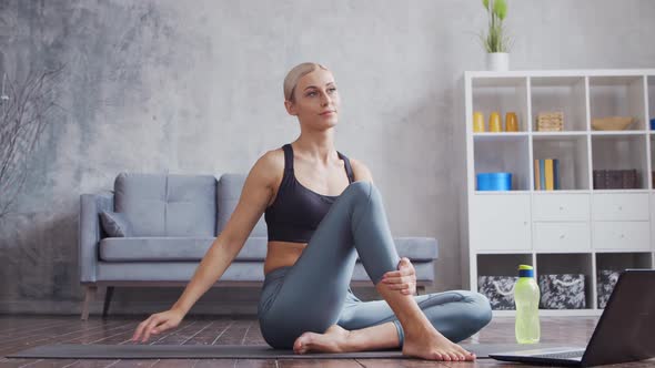 Young and sporty girl in sportswear is doing exercises in home interior.