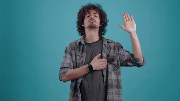 Curly Young Man Who Greets with His Hand Looking Into the Room Finally Smiles