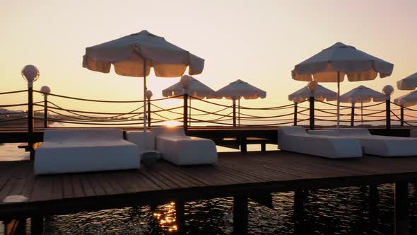 Wooden Pier with Sunbeds and Umbrellas at Sunset.