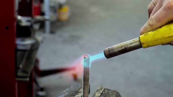 Fire of gas burner heats up red-hot the metal bolt