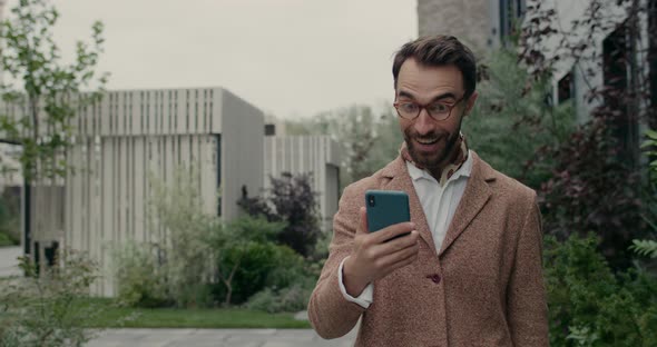 Crop View of Guy in Glasses Rejoicing and Doing Yes Gesture While Checking Smartphone Content