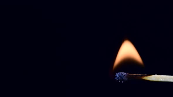 wooden match being lit against black background with large copy space