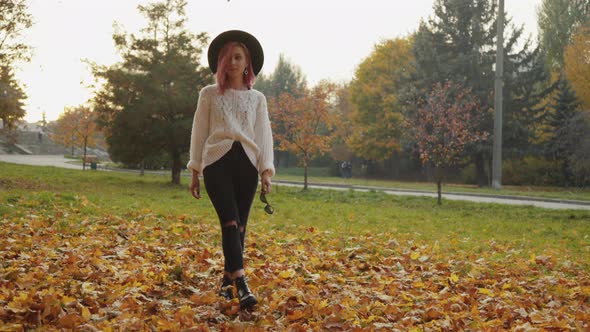 Attractive Girl Walks Among Autumn Crimson Maple Leaves at Park