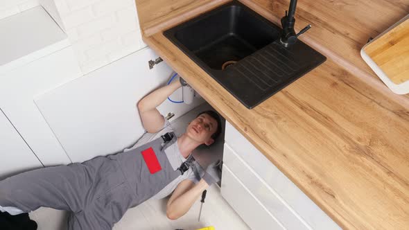 Employee Unscrews Details Repairing Waste Trap Under Sink