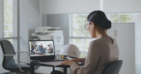 Back View of Female Architect Having Online Video Conference on Laptop in Office