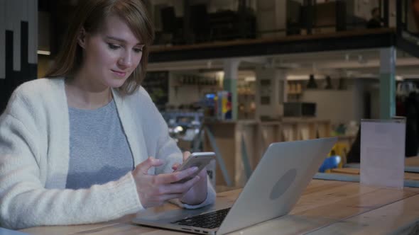 Young Woman Using Smartphone in Cafe Typing SMS