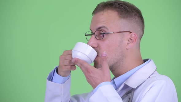 Closeup Profile View of Happy Handsome Man Doctor Drinking Coffee