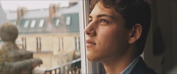 Daydreaming young man staring at the cloudy sky from his home