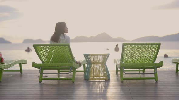 A Woman Enjoys the View of Coming Sunset in Front of an Infinity Swimming Pool