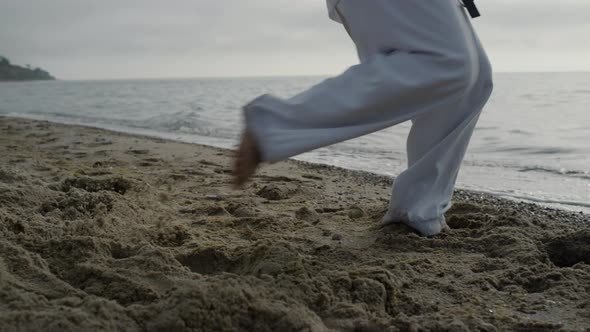 Unknown Man Legs Making Karate Kicks on Sand Close Up