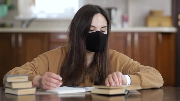 Girl in a Respiratory Mask Studying Distantly While Sitting at a Table