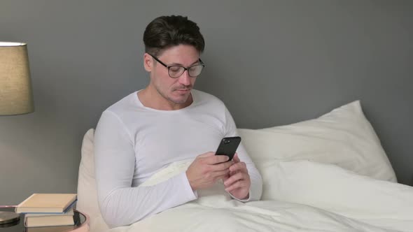 Smartphone Use By Serious Middle Aged Man in Bed