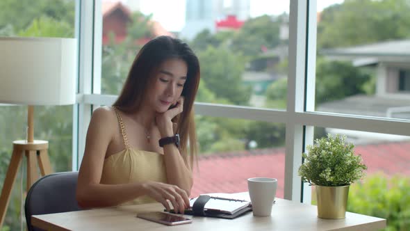 Young pretty woman writing in appointment book at coffee shop