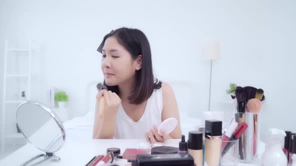 Young Asian woman use cosmetics review make up tutorial broadcast live video to social network.