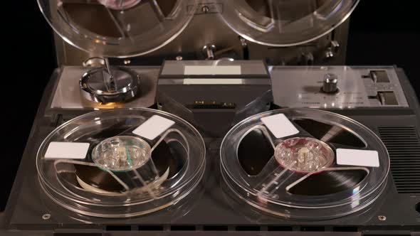 Two Reel to Reel tape recorders playing music together with four tapes