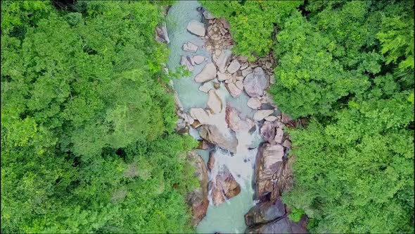 Aerial View Over River with Rocks Between Thick Jungle