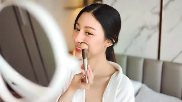 Happy attractive asian woman apply skincare cream on face